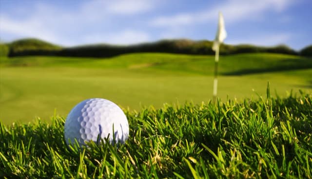 Close-up of a golf ball on a green fairway with a flag in the background near Tahoe Vista, CA.