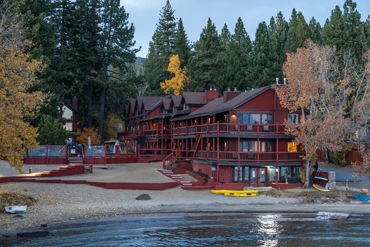 Cozy living room with gas fireplace, sofa, and lake views through corner windows at Tahoe Edgelake Beach Club