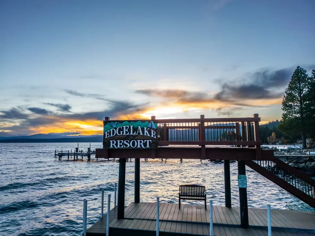 Bench on lakeside deck at sunrise with golden leaves and pier reflecting on Lake Tahoe